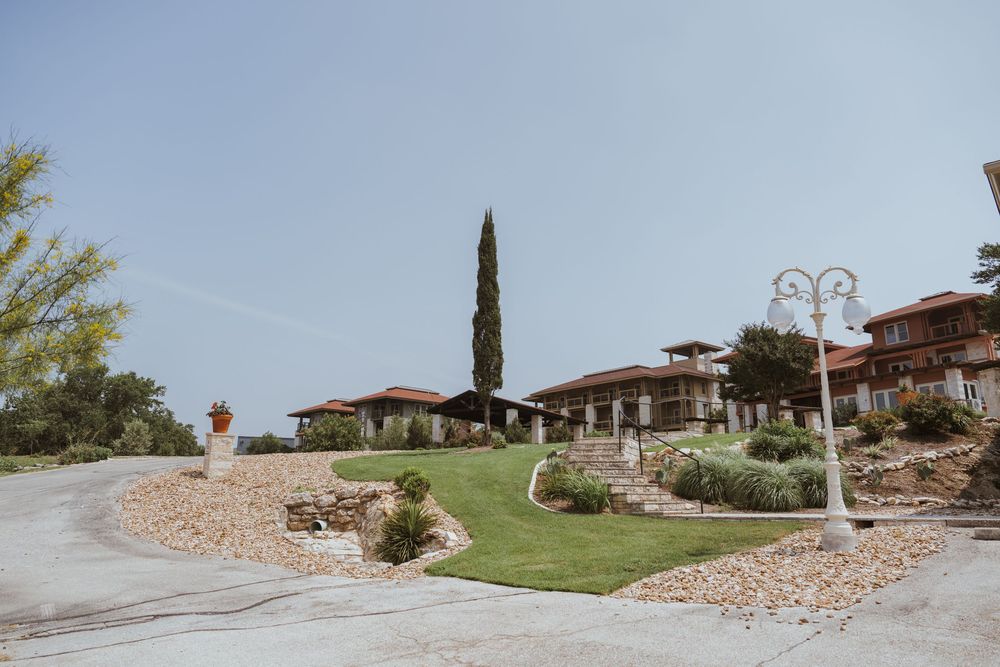 Mediterranean-style wedding venue with stone walls and cypress trees set against a blue sky.