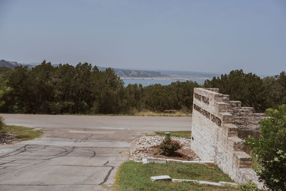 Scenic overlook of a lake with stone wall and trees in the foreground.