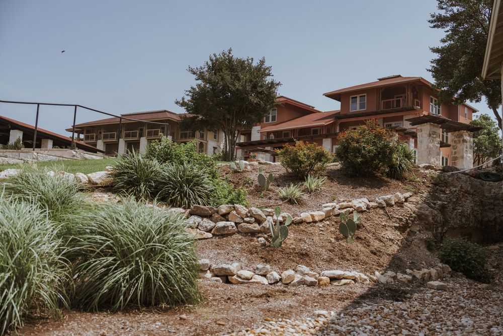 Rustic hillside wedding venue with terraced landscaping and ornamental grasses.