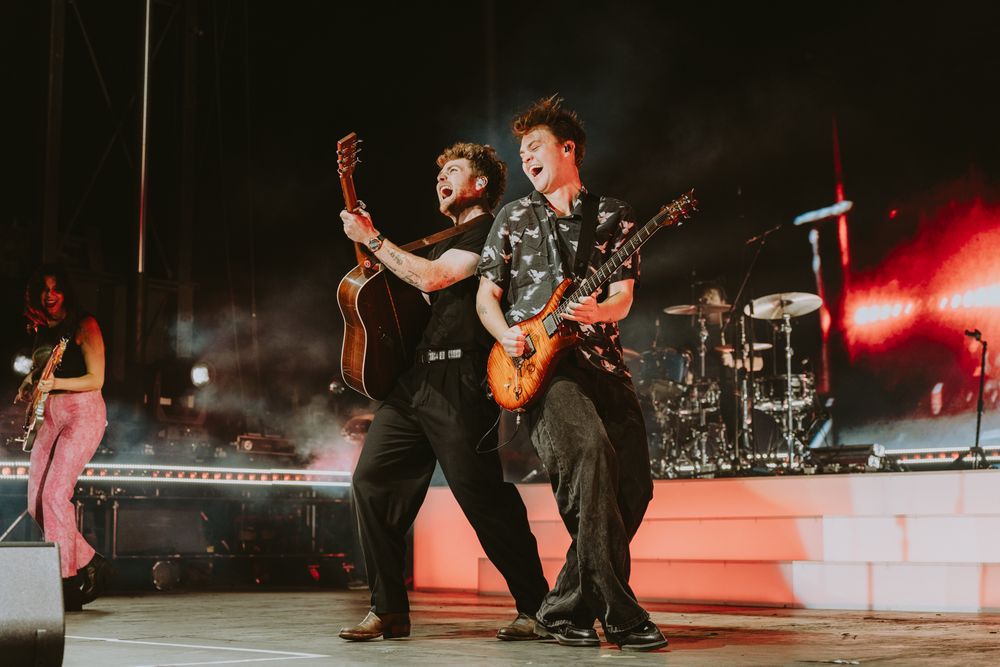 Concert performance on stage with dramatic red lighting and silhouetted musicians.