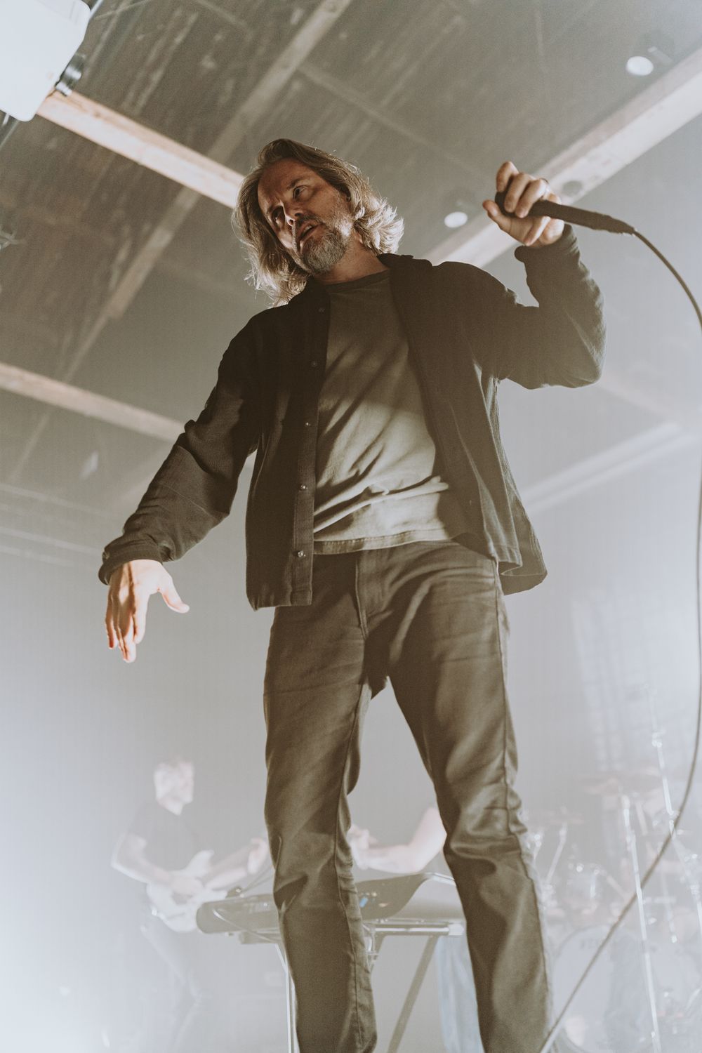 Vocalist performs passionately on stage with microphone during atmospheric concert performance.