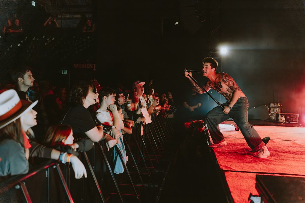 Concert performer engages with enthusiastic crowd during energetic stage performance.