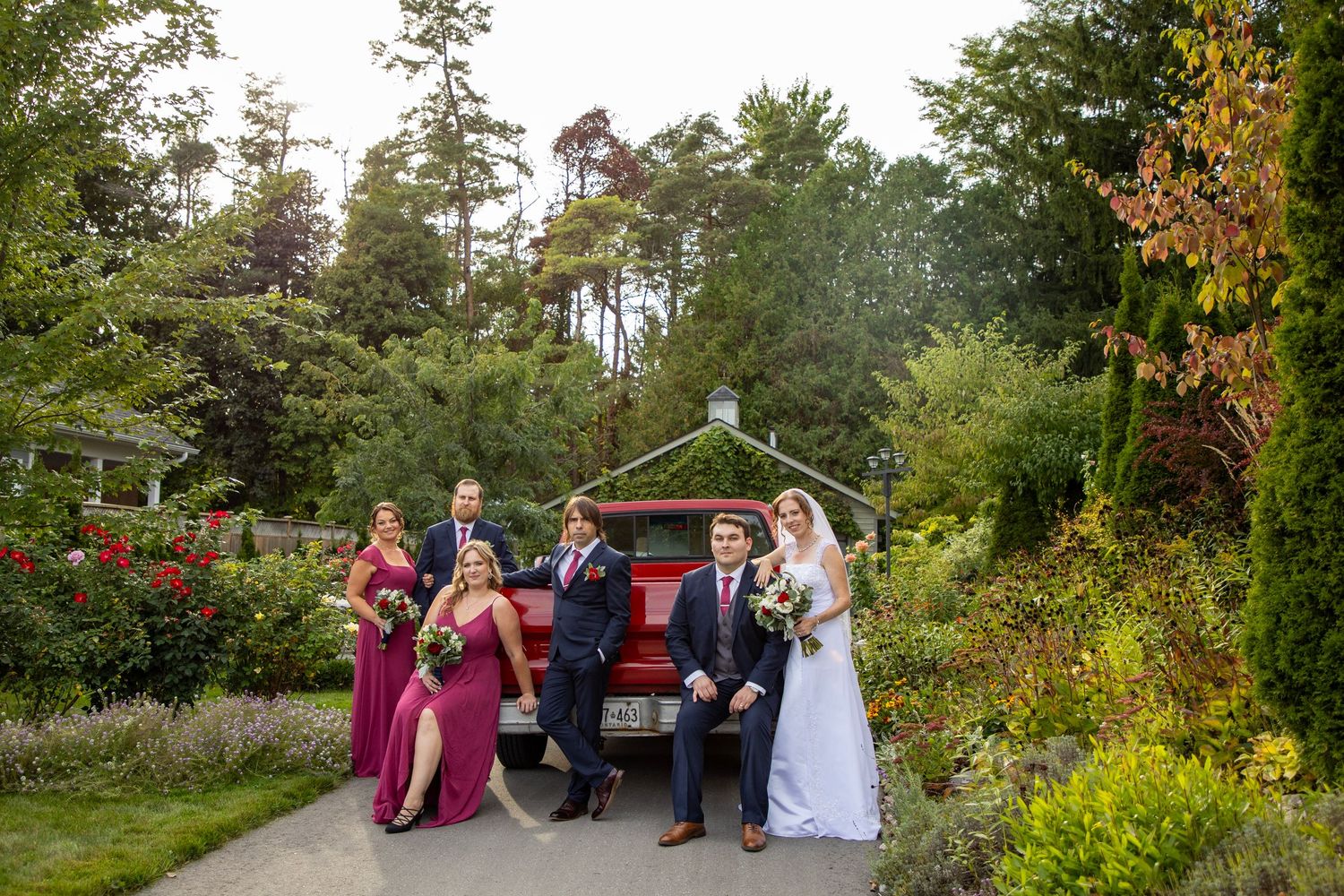 bridal party strategically placed in front of the trunk of a vintage red truck