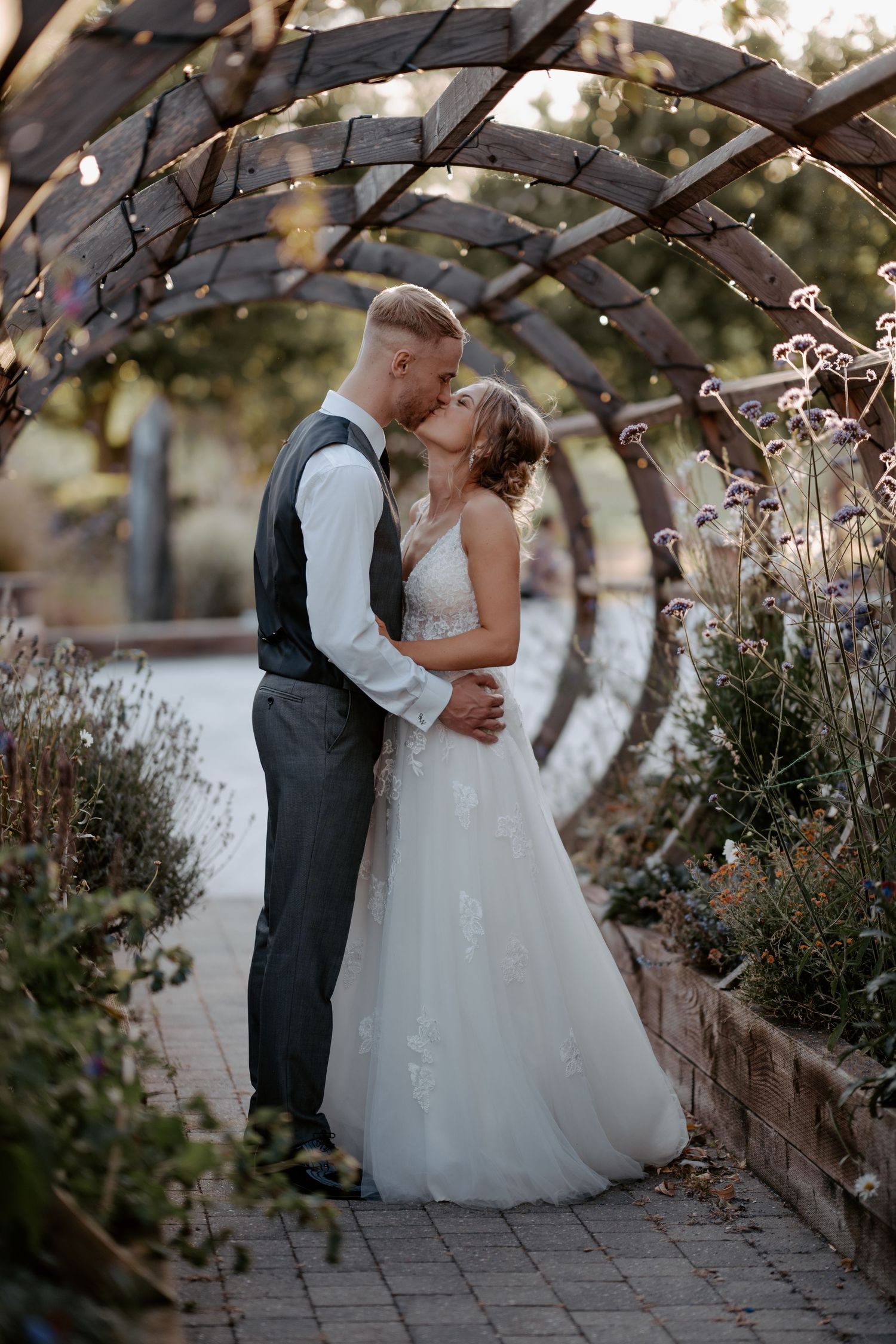 Wedding guests celebrate during a reception in a rustic brick venue with lattice wall decor and greenery.