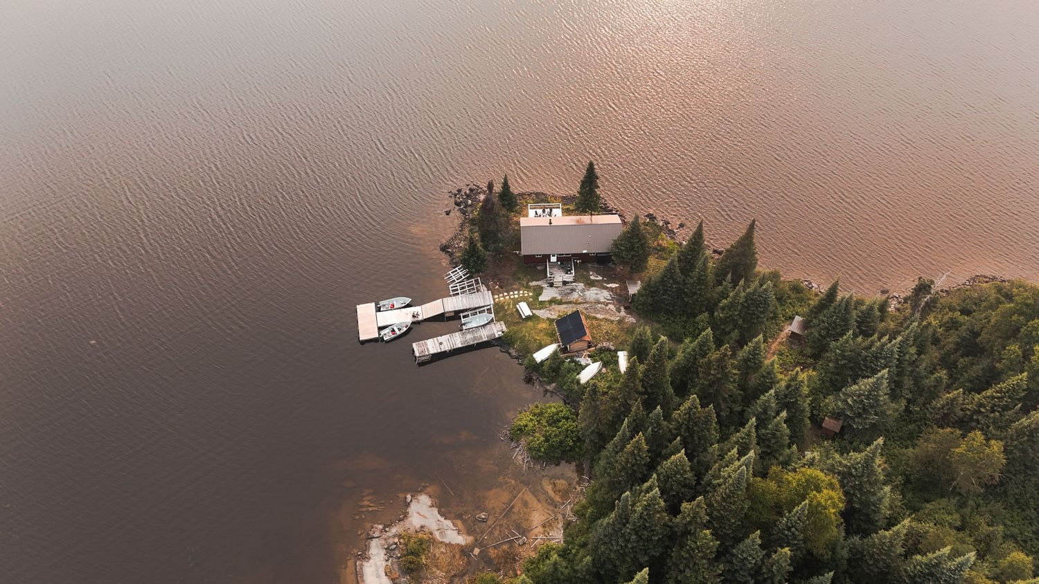 Drone view of lakeside properties and docks during golden hour.