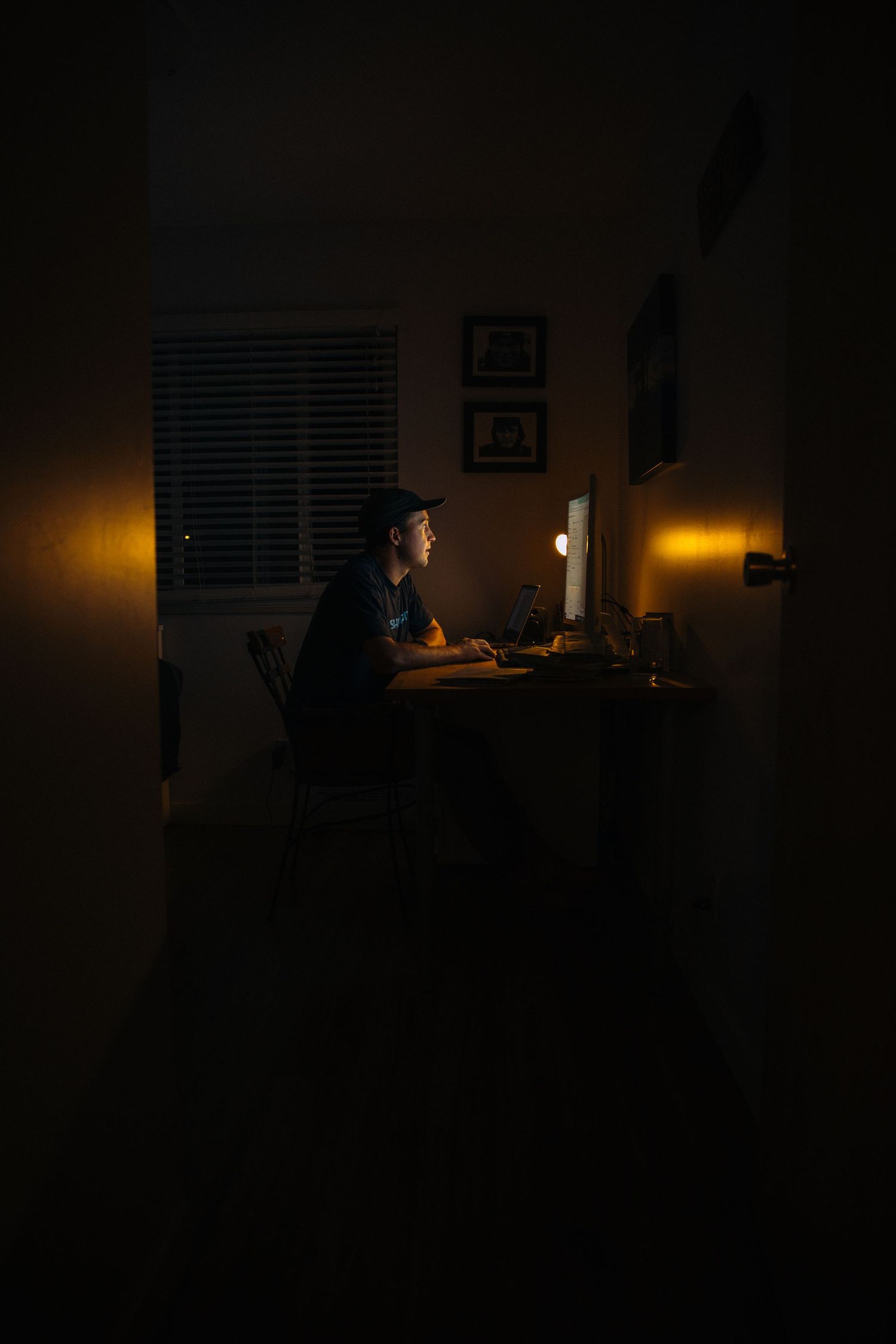 Person working late at night at a desk illuminated by warm lighting.