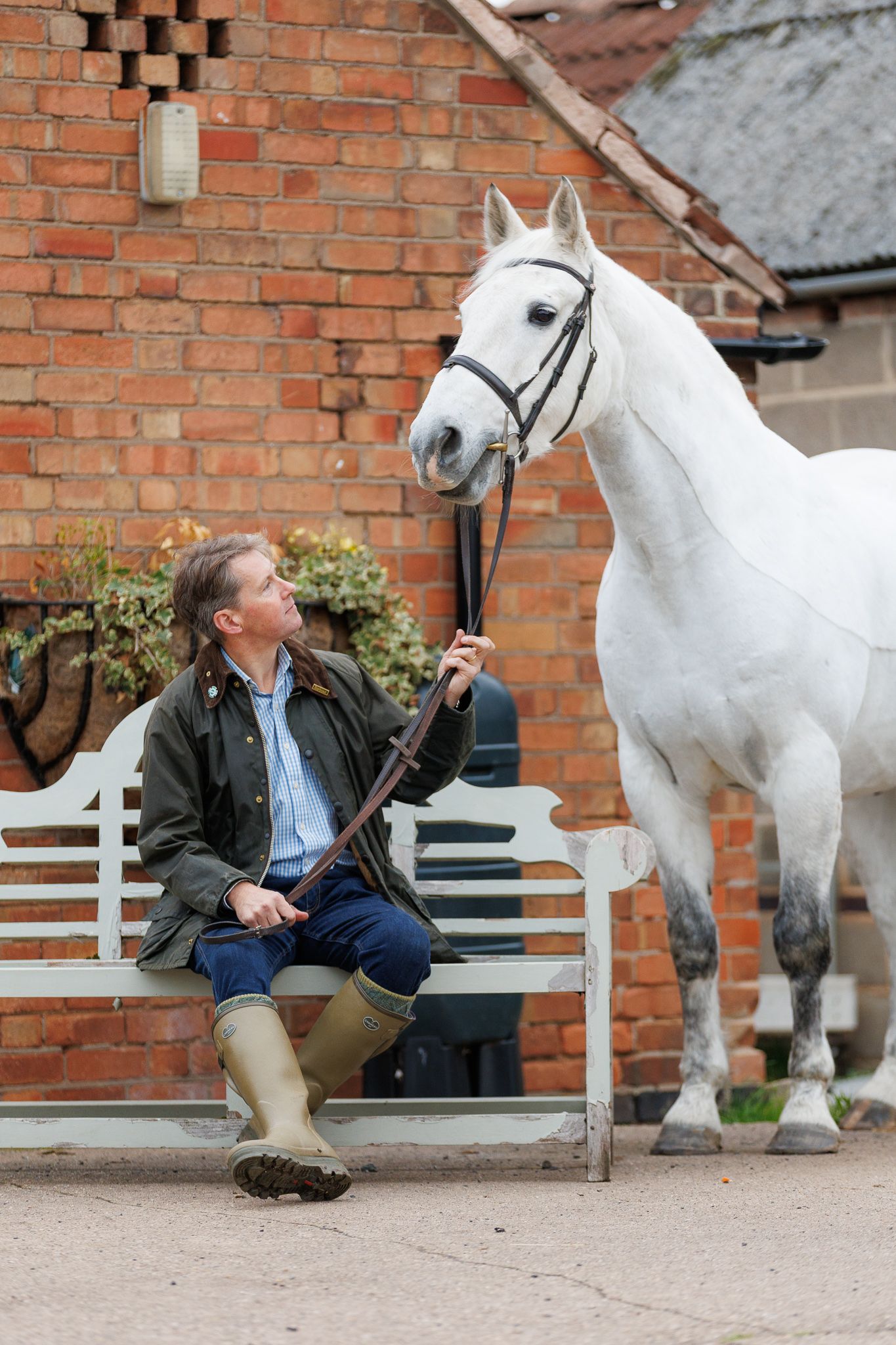 A horse and its rider enjoy an outdoor photoshoot session near rustic wooden fencing on a sunny day.