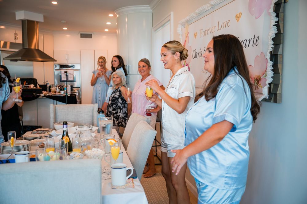 A group gathers around a kitchen counter during a cooking class or demonstration in a bright modern space.