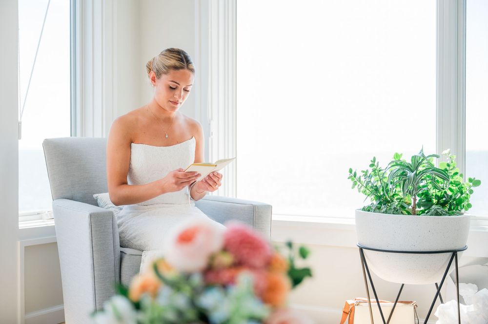 Elegant bridal suite with white decor, floral arrangements, and natural light streaming through large windows.