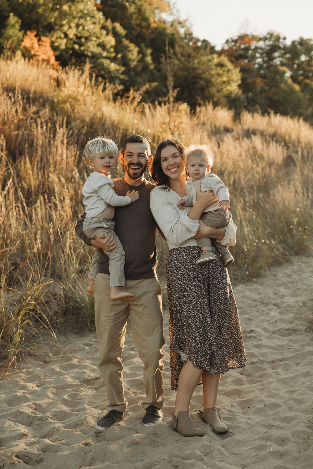 A group enjoying a warm sunset moment together on a sandy beach path with golden grasses in the background.