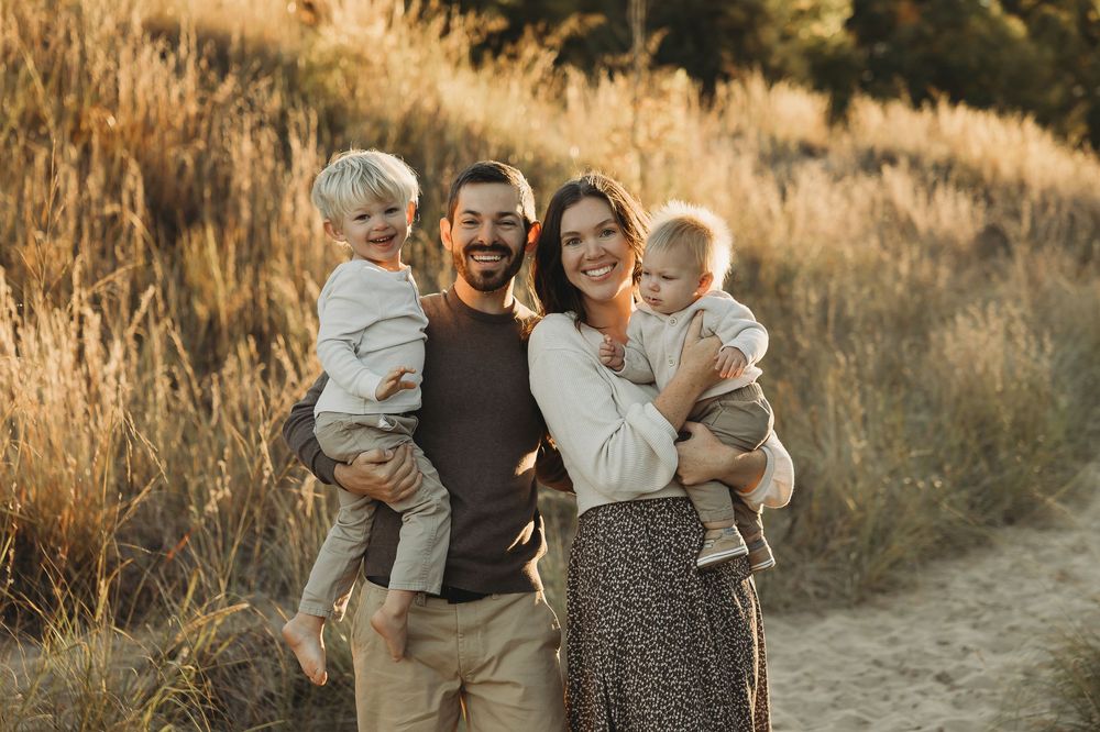 A family shares joyful moments together in a golden field at sunset during an outdoor photo session.