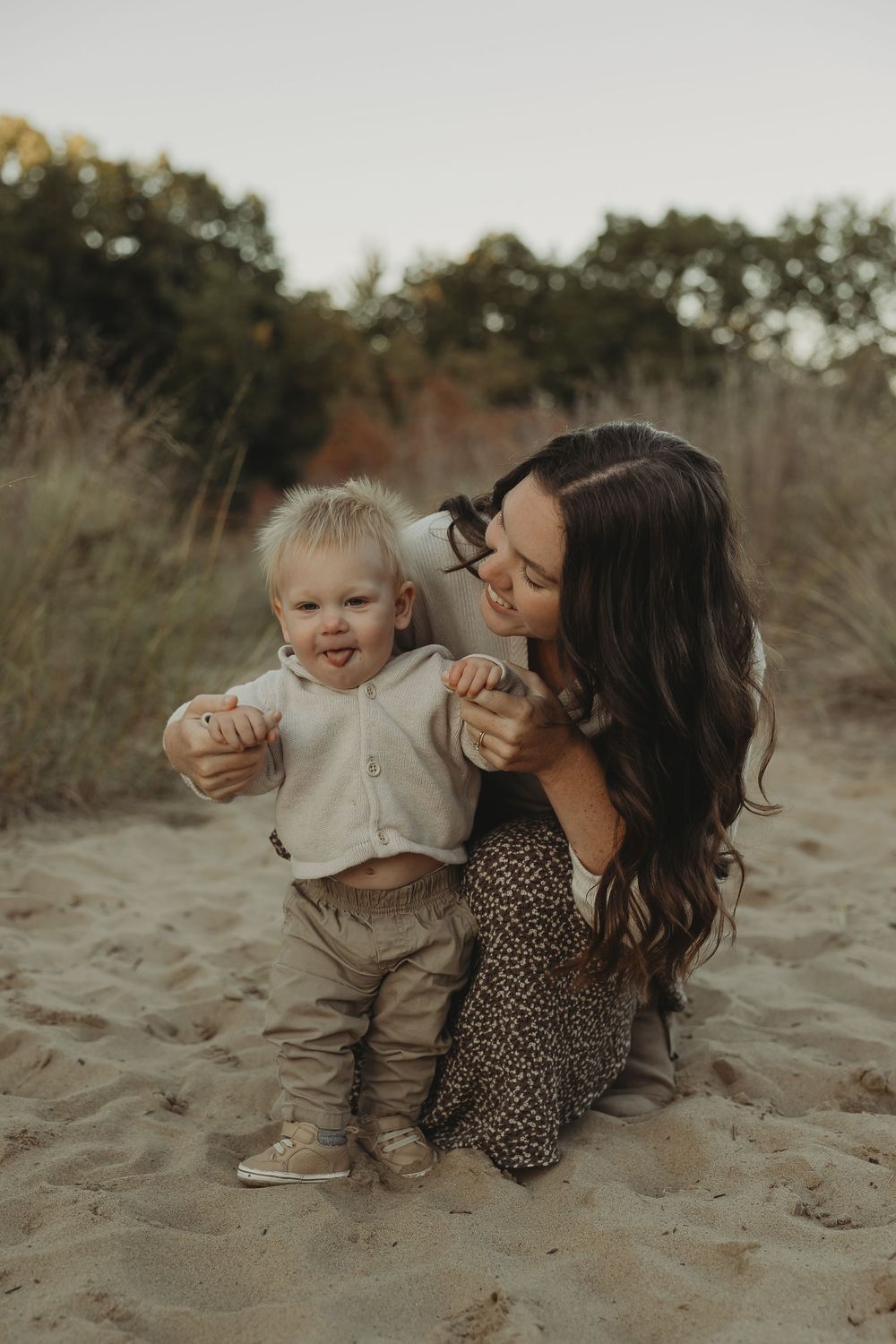 A heartwarming moment between parent and child playing together on sandy dunes during golden hour.