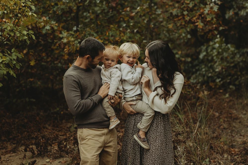 A couple embraces in a romantic autumn forest setting during a photoshoot.