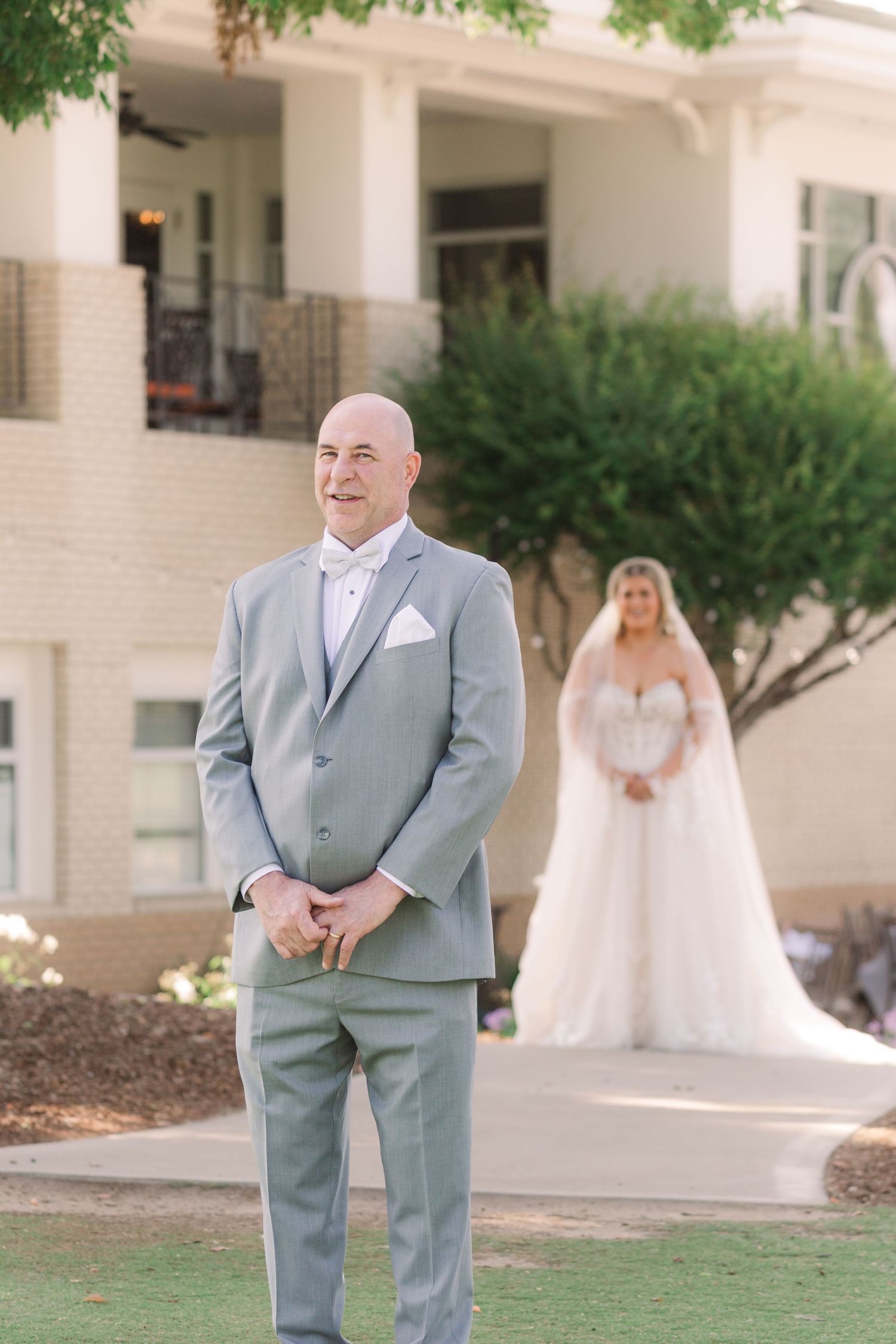 First look wedding moment captured outside elegant white columned building.