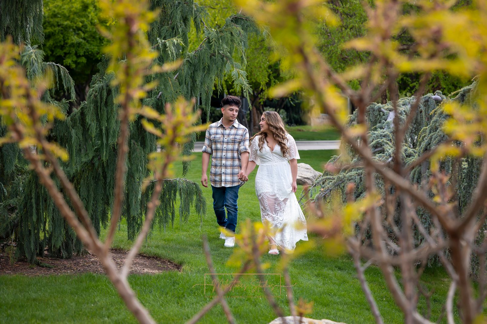 couple walking together framed by flowering tree limbs