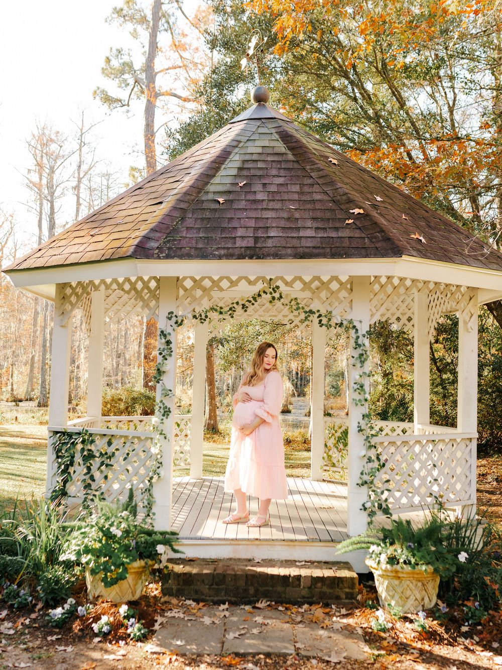 A scenic white gazebo with lattice details surrounded by fall foliage.