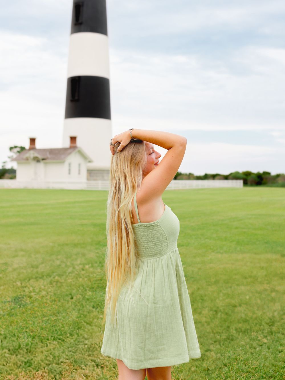 A mint green sundress against a black and white lighthouse backdrop on a grassy field.