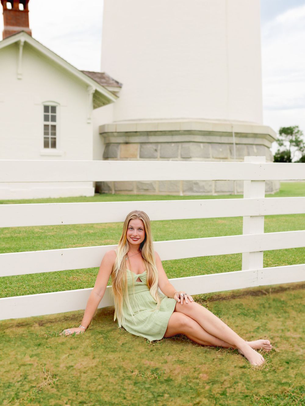 Summer portrait by a white fence and lighthouse keeper's house.