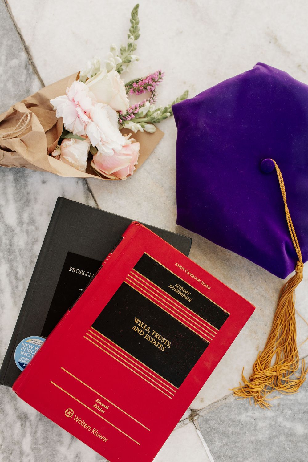 Graduation memorabilia including diplomas, tassels and flowers arranged on marble surface.