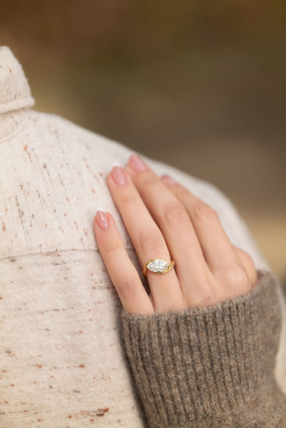 Close-up of an engagement ring with marquise diamond in gold setting on a woman's hand.