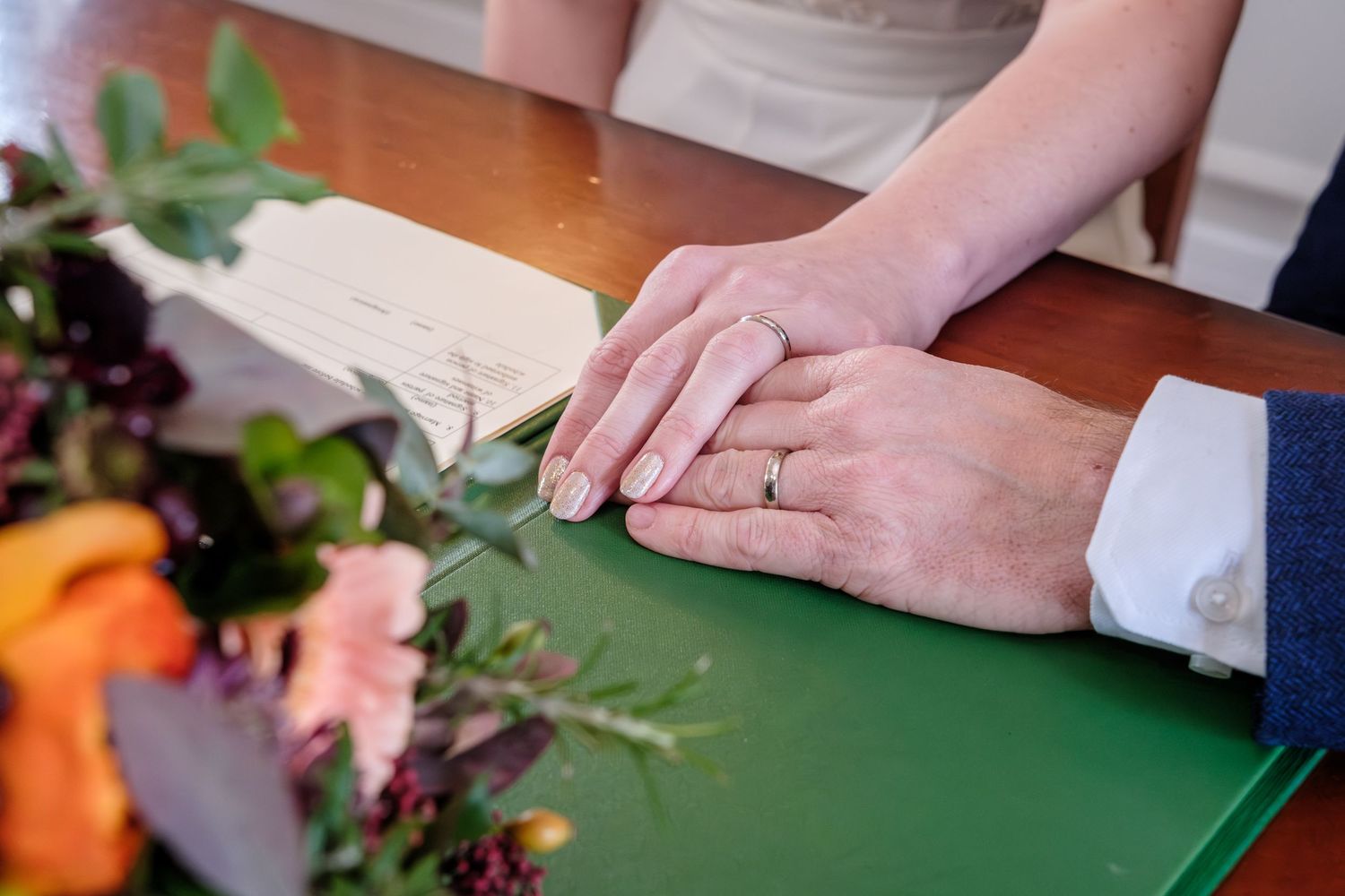 Hands chopping fresh vegetables on a green cutting board with a sharp knife in a bright kitchen setting.