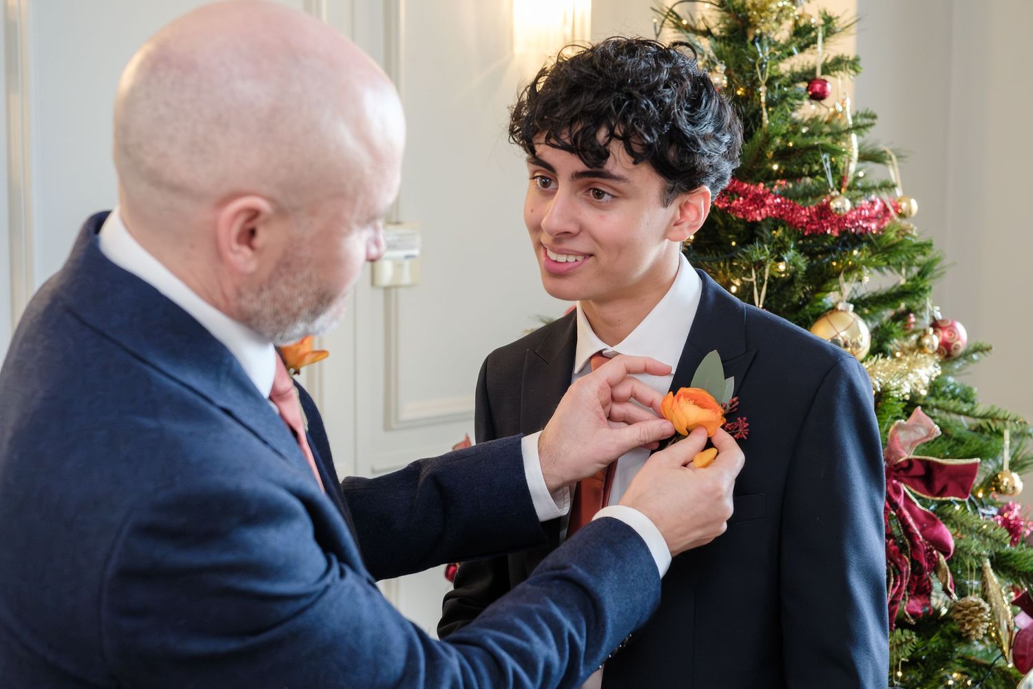 A sequence of four similar photos showing people in formal attire interacting near a decorated Christmas tree.