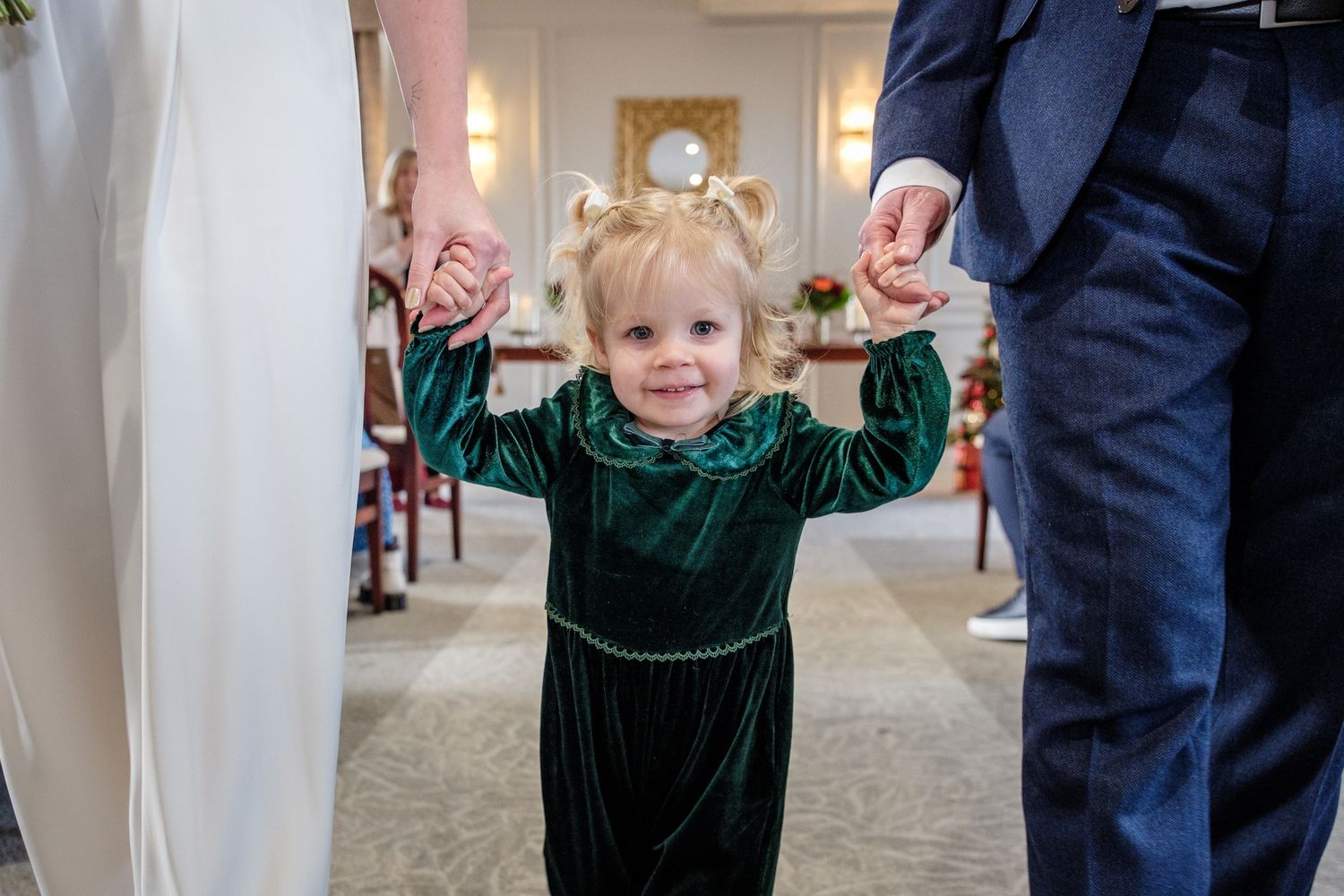A series of candid wedding moments showing a small child in green interacting with adults in formal attire.