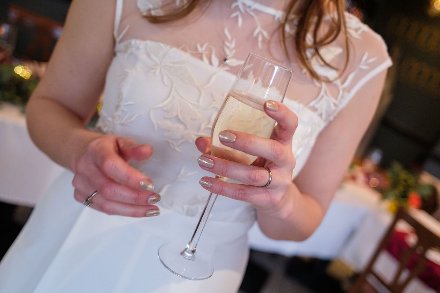 Two champagne glasses clink together in celebration during an outdoor gathering at sunset.