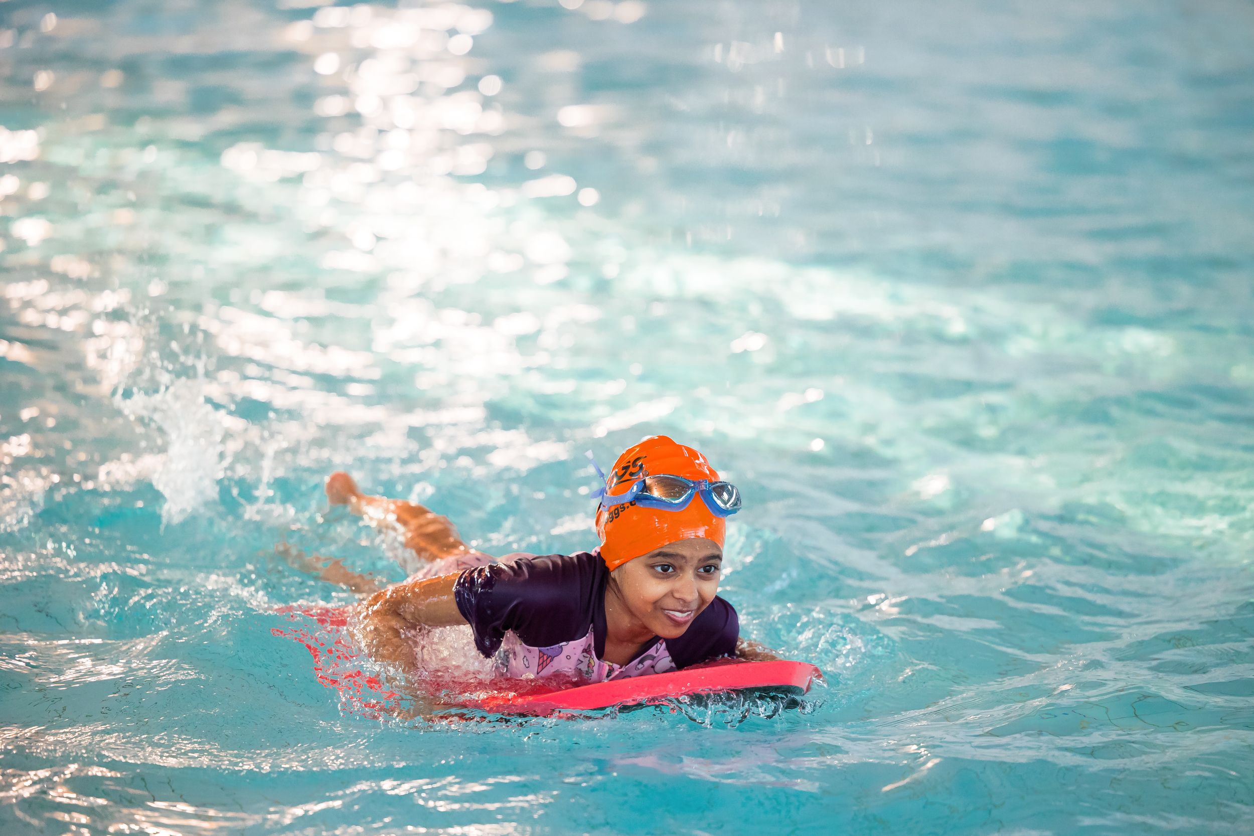 Swimmers practicing freestyle stroke in a bright blue indoor pool.