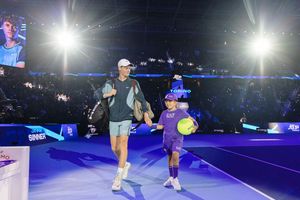 Jannik Sinner competing on an illuminated blue tennis court during a nighttime match.