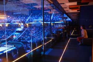 Arena stadium seating with blue lighting and dramatic atmosphere during an event.
