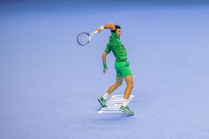 Tennis player executing a powerful serve motion against bright blue sky background.