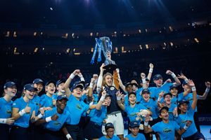 Tennis player Tsisipas celebrating winning the ATP finals with trophy under stadium lights with the ball kids.