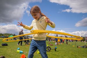 People participating in outdoor team building activities with yellow ropes under cloudy skies.
