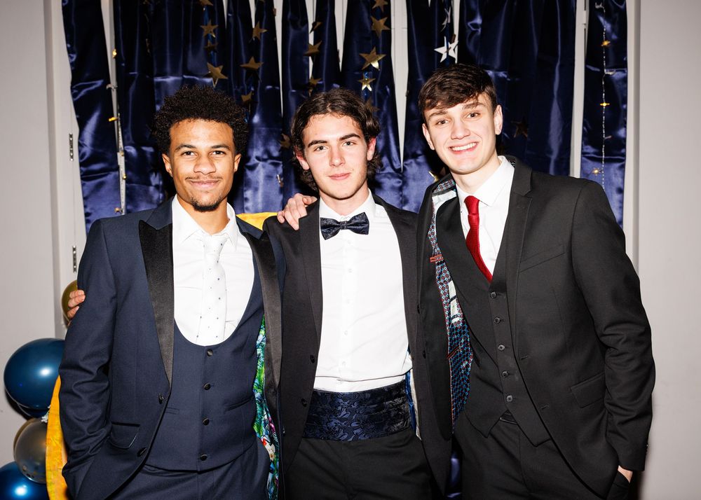 Group of formally dressed guests posing together at an elegant indoor event.