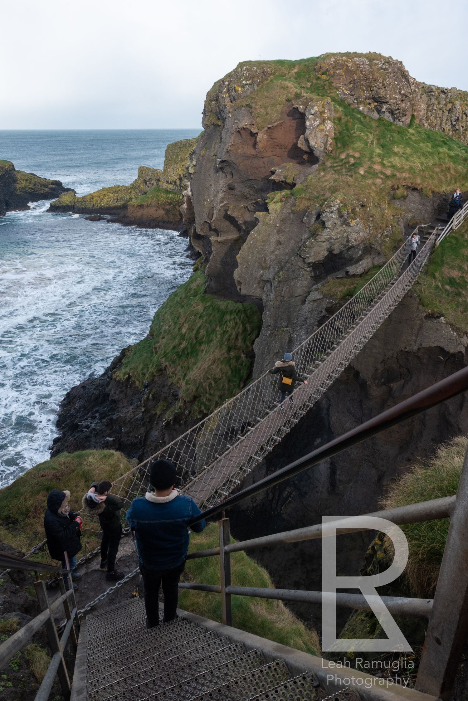 Visitors traverse a dramatic rope bridge along rugged coastal cliffs at Carrick-a-Rede in Northern Ireland with Leah Ramuglia Photography