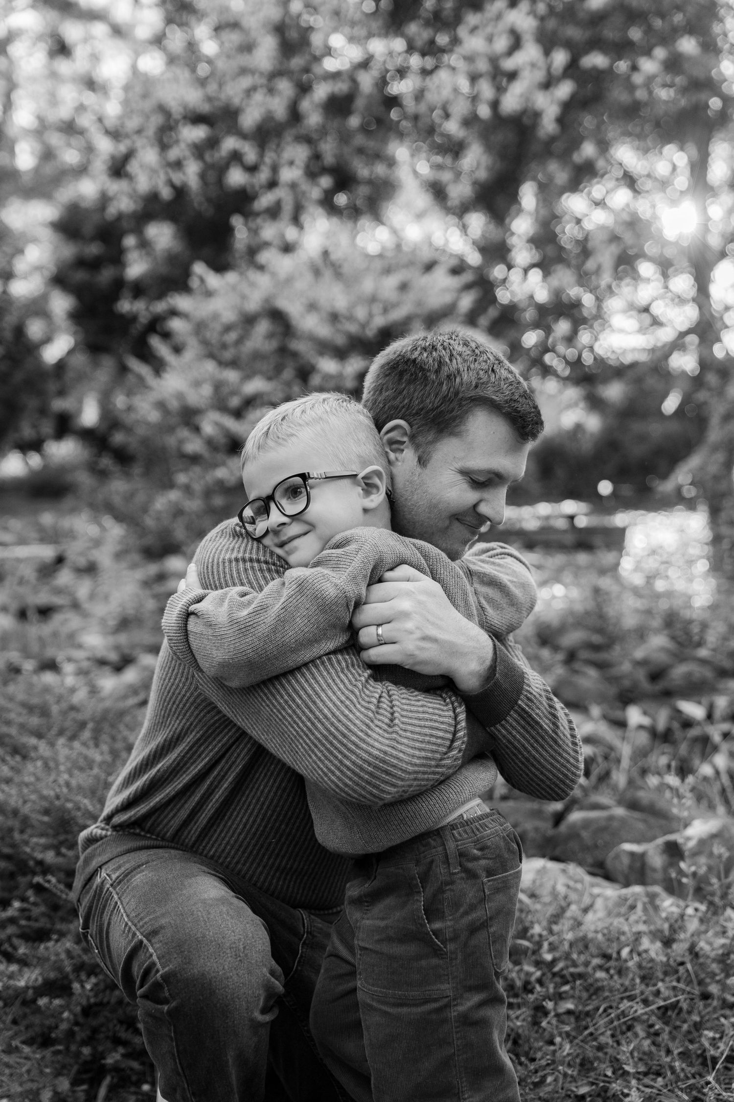 Black and white photo series showing two people embracing in an emotional moment outdoors among foliage.