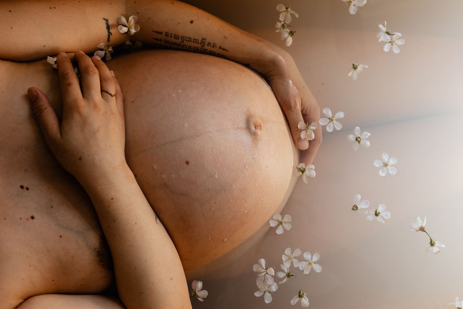ventre rond d'une future maman prenant un bain de lait fleuri a la fin de sa grossesse, un moment doux et authentique, une photo artistique