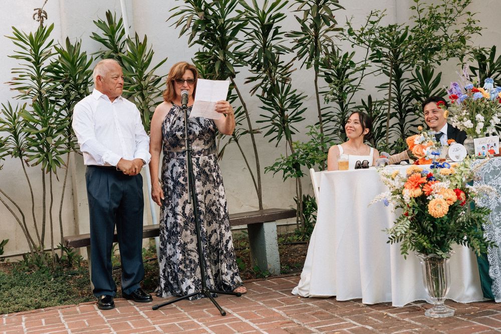 A wide view of the emotional open mic toasts being given at the courtyard wedding reception, captured by Santa Barbara wedding photographer.