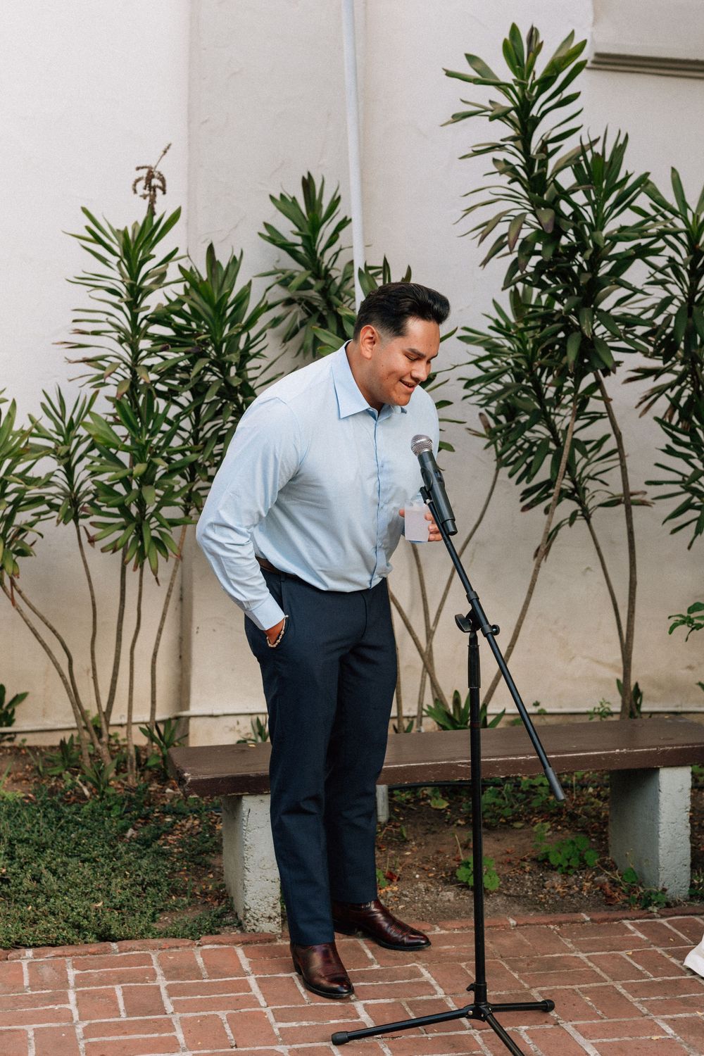 A candid film shot of the emotional open mic speaker holding the microphone during the Unitarian Society courtyard reception toasts.
