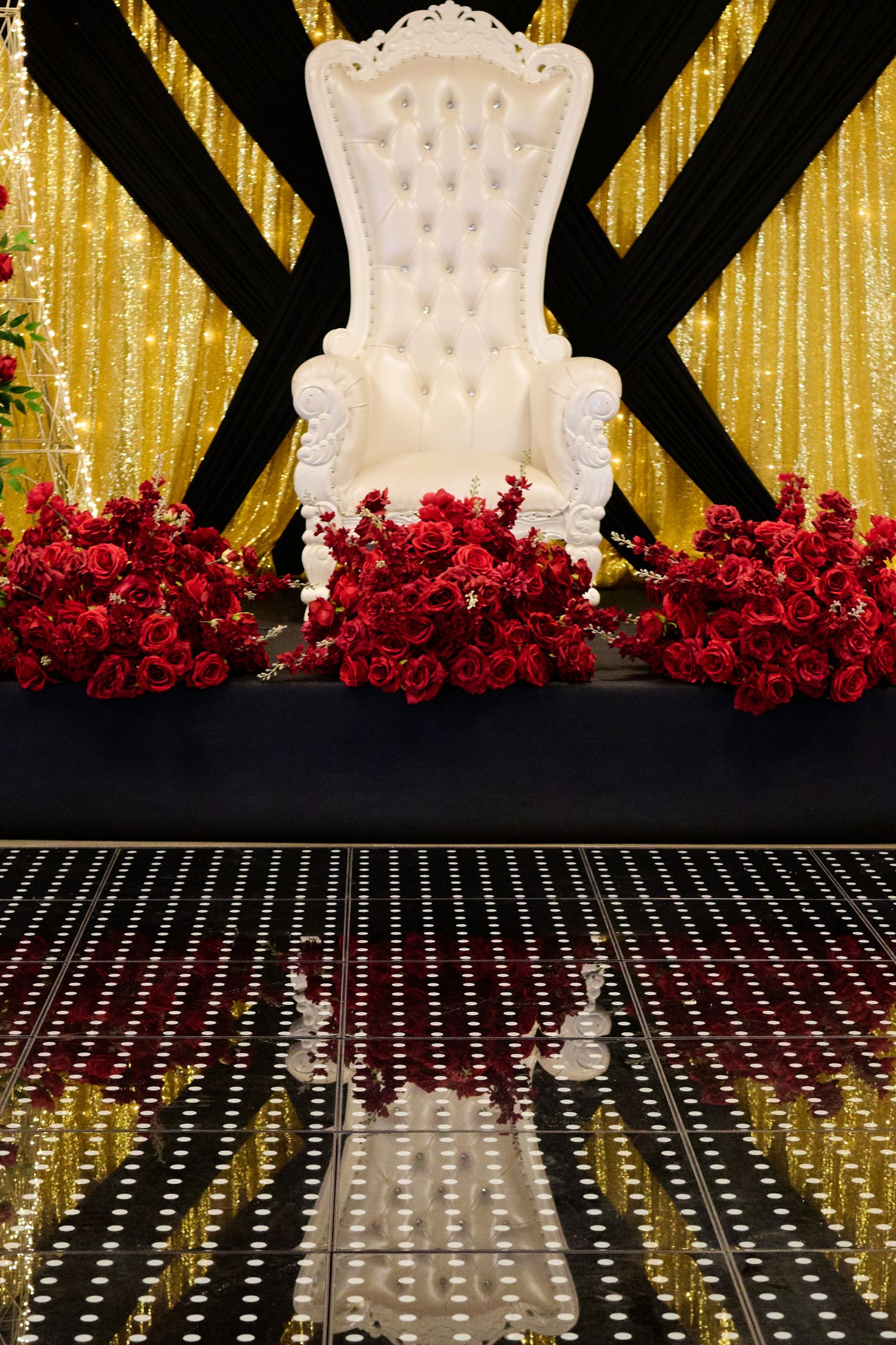 Elegant green cake decorated with gold accents, metallic baubles and a delicate fan-shaped topper against red curtain backdrop.