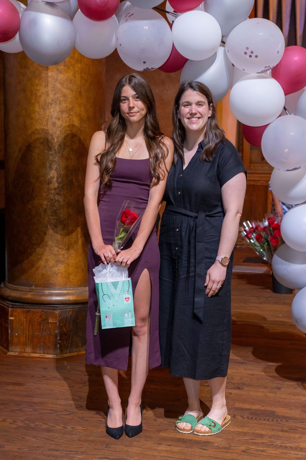 A balloon arch decorates an indoor venue as attendees gather for a celebration.