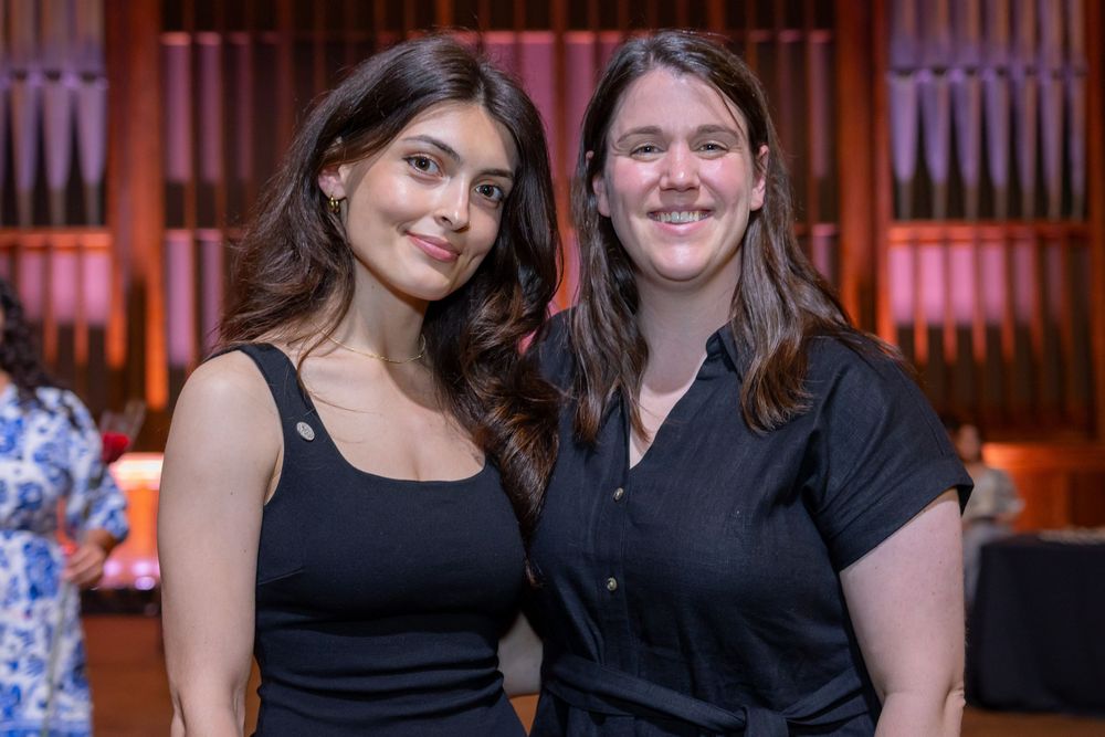 Attendees in formal attire pose together at an indoor celebration event.