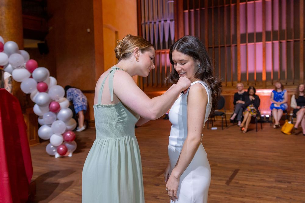 People gather in formal attire under decorative lighting at an indoor venue.