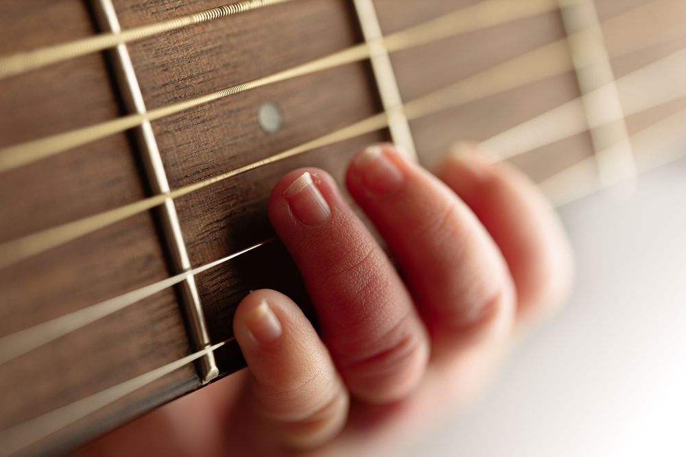 Close-up sequence of fingers pressing down on guitar frets showing proper finger placement technique. – newborn photographer Paloma Schell