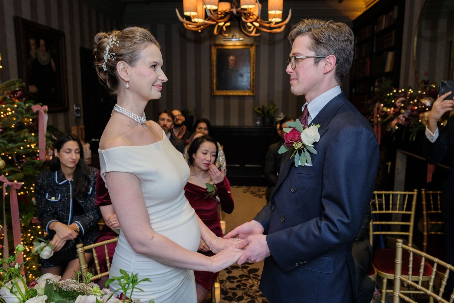 A couple dances together in an elegant ballroom setting with chandeliers and holiday decorations.