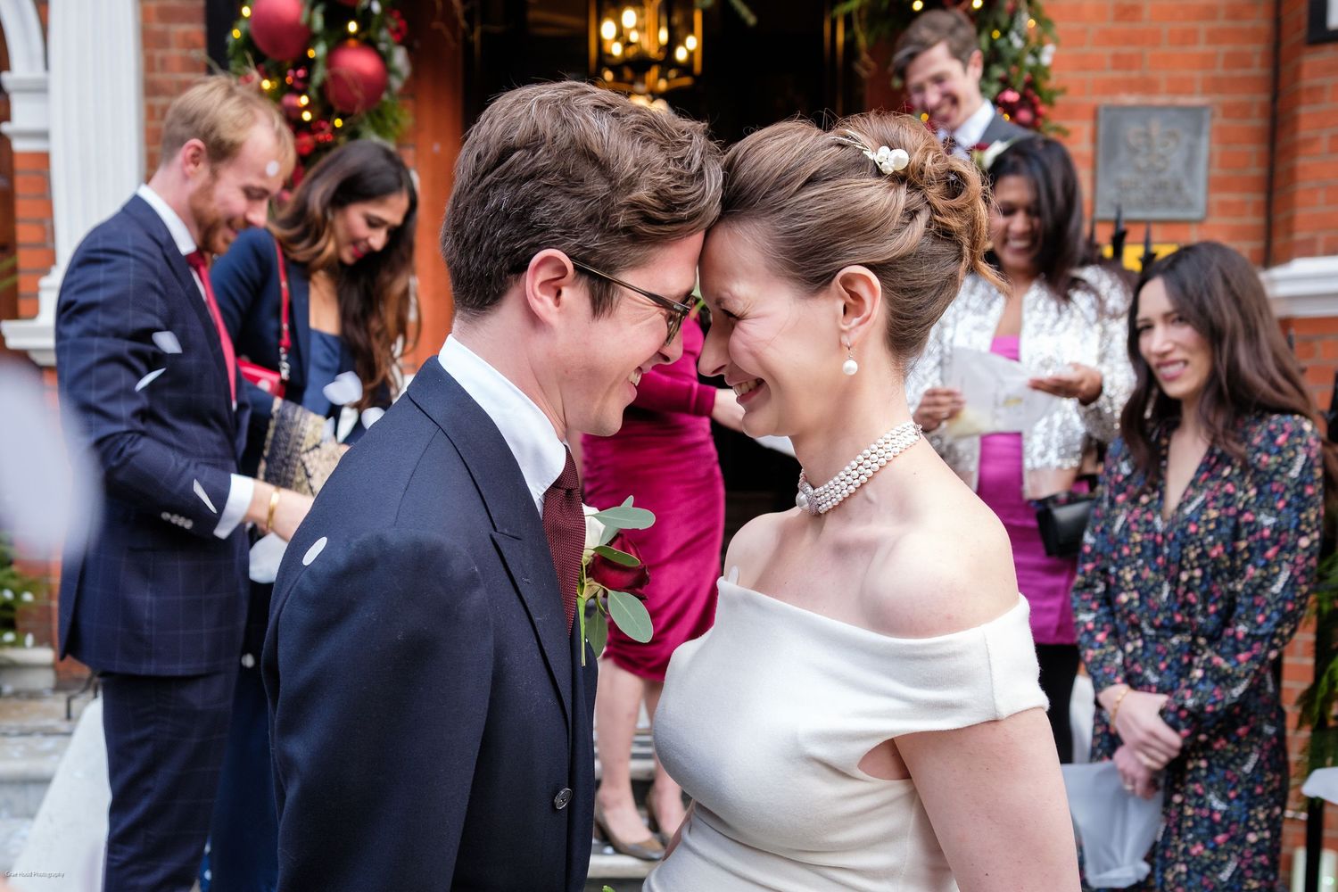 A romantic first dance between newlyweds surrounded by guests in a brick-walled venue with Christmas decor.