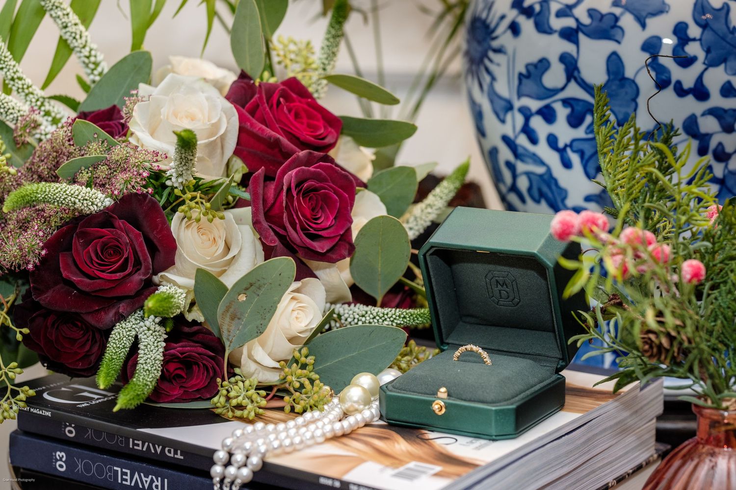 Vintage books and dark red roses arranged with pearls and decorative elements in a romantic flatlay composition.