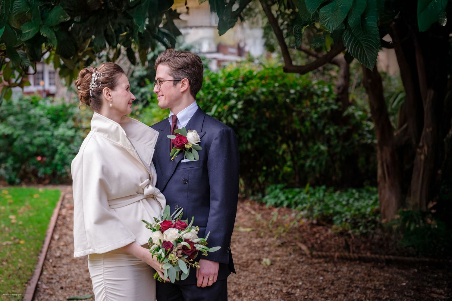 A couple shares intimate moments in a lush garden setting during their wedding celebration.
