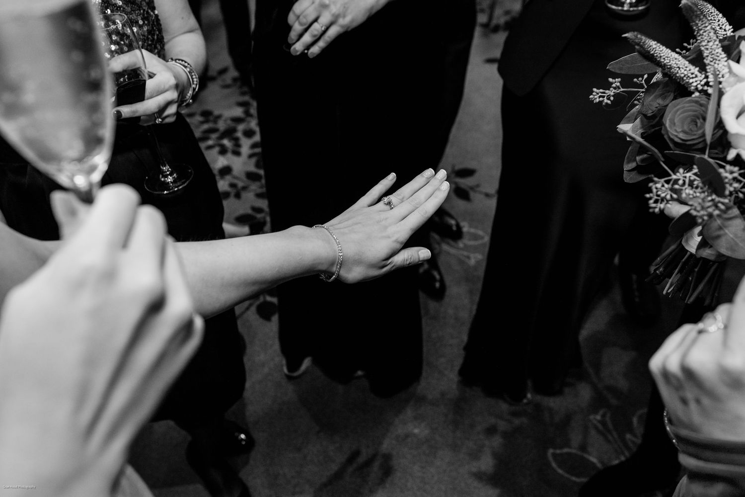 Black and white photo showing hands and drinks at a social event.